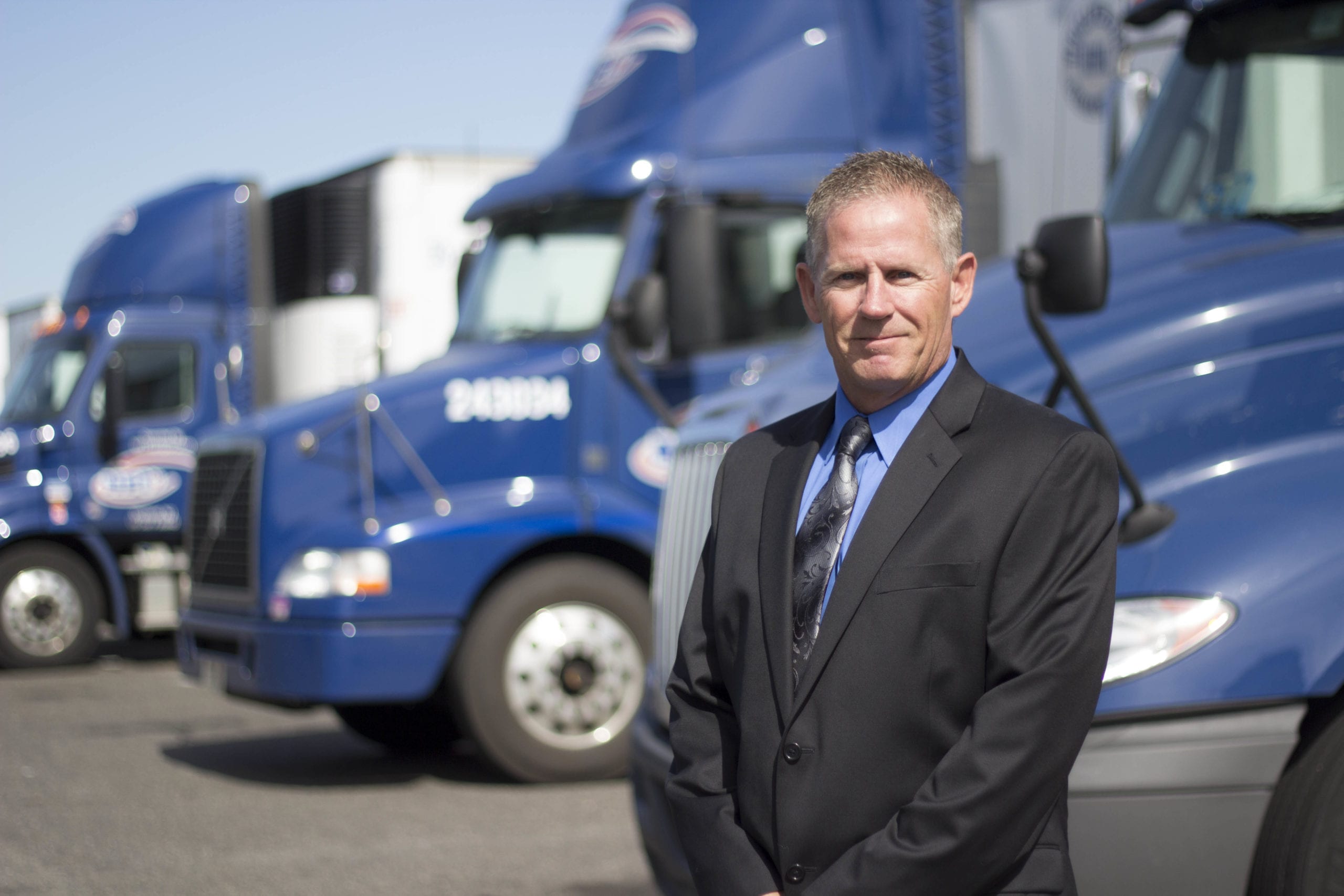 Bill Bliem standing in front of NFI trucks