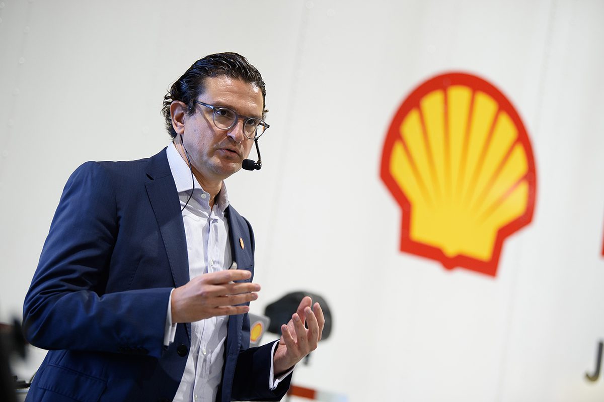 man with head mic standing in front of Shell logo