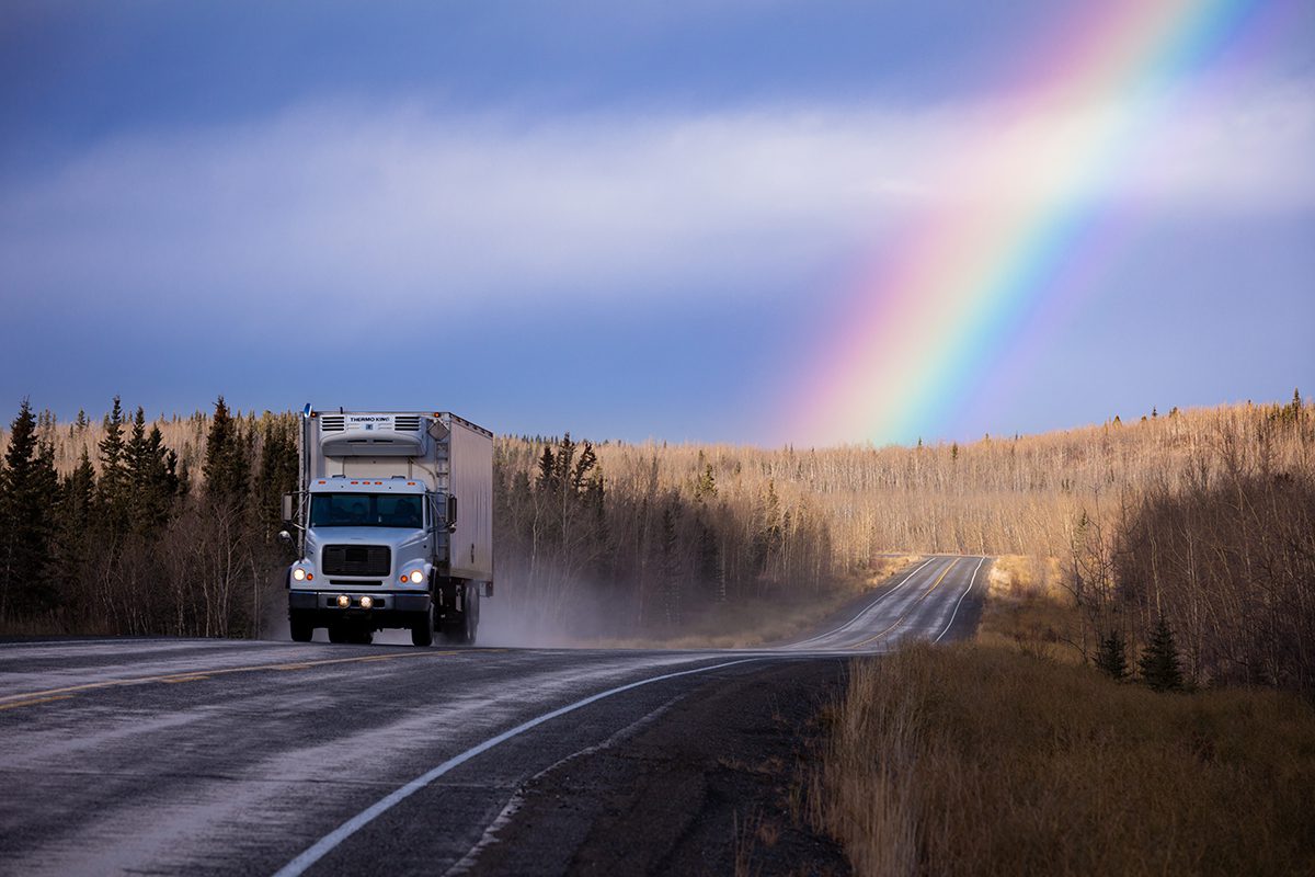 white semi truck on road in rainbow Yukon landscape