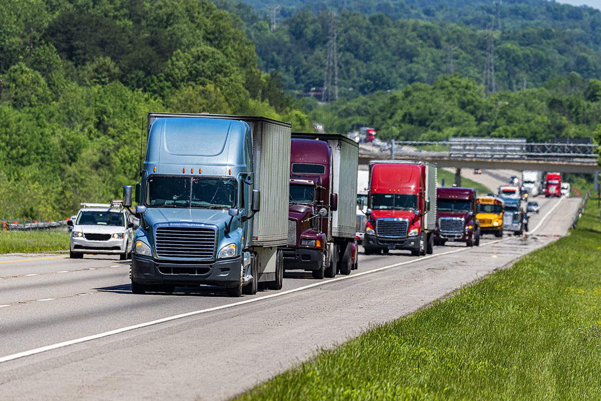 Blue, purple and red Semi trucks climbs Interstate Hill In Heavy Traffic